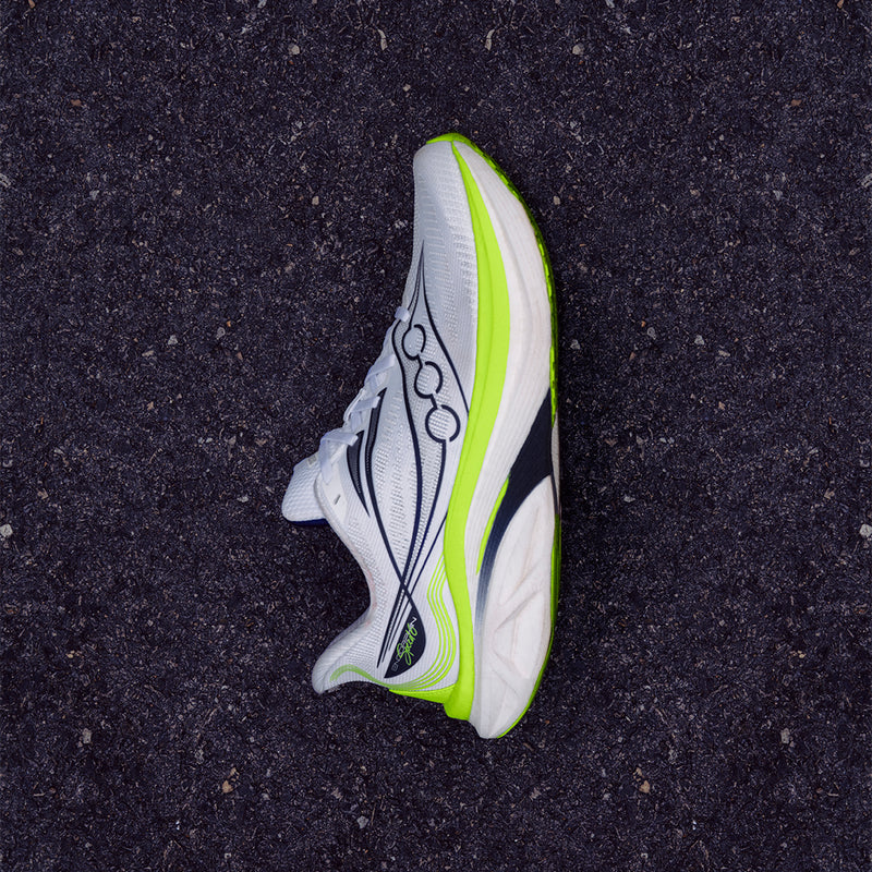 White Saucony Endorphin Speed 6 running shoe with a neon yellow midsole, lying on asphalt